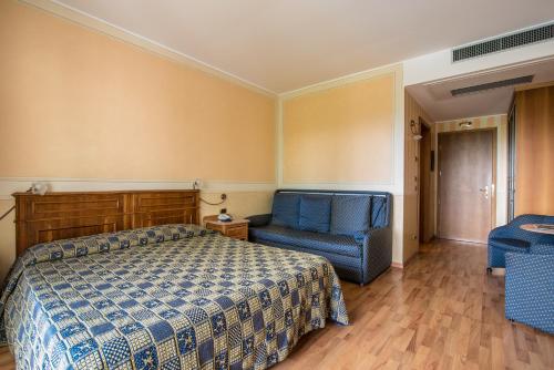 a bedroom with a bed and a blue chair at Hotel Porta Del Sole in Soiano del Lago