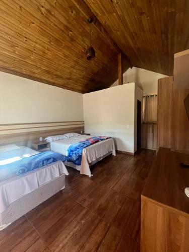two beds in a room with wooden ceilings at Hotel Fazenda Recanto in Ouro Branco