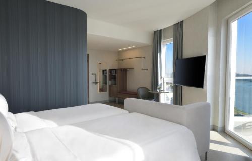 a hotel room with a white bed and a window at Novotel Lubumbashi in Lubumbashi