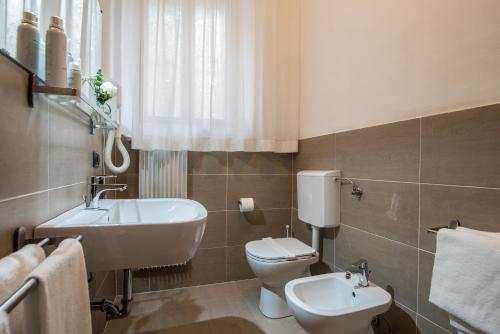 a bathroom with a white toilet and a sink at Hotel Porta Del Sole in Soiano del Lago