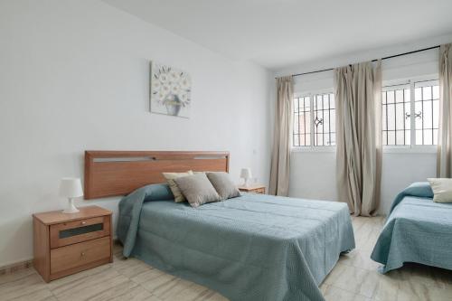 Un dormitorio con dos camas y dos ventanas. en Piso Ureba, bajo, en Conil de la Frontera