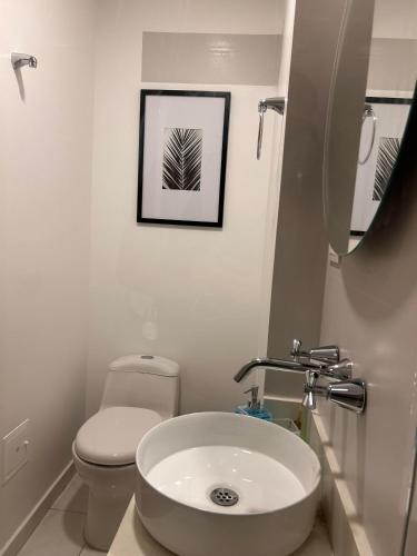 a bathroom with a sink and a toilet and a picture at Apartamento con piscina climatizada, excelente ubicación, luz natural, acogedor y con estilo in Bogotá