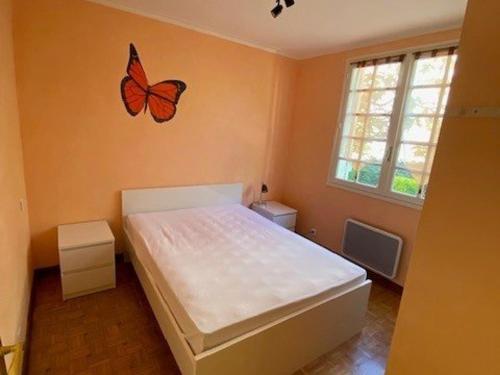 - une chambre dotée d'un lit avec un papillon sur le mur dans l'établissement Charmant T3 avec Jardin, Centre de Valras-Plage, proche Plage et Commerces, 5 Pers. - FR-1-701-9, à Valras-Plage
