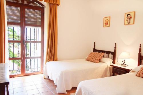 a bedroom with two beds and a window at Schönes Ferienhaus mit Sonnenterasse und Pool in Lora del Río