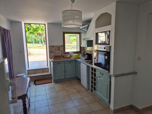 une cuisine avec des placards verts et une grande fenêtre dans l'établissement Gîte entre Rieu et Fournache, à Mirabel-aux-Baronnies
