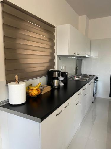 a kitchen with white cabinets and a black counter top at La Terra Luxury apartment in Kivérion