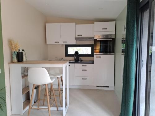 une cuisine avec des armoires blanches et une table et des chaises dans l'établissement La Pinède de Venelles, à Venelles