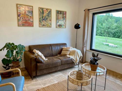 a living room with a brown couch and two tables at Maison de charme à la campagne in Montpezat