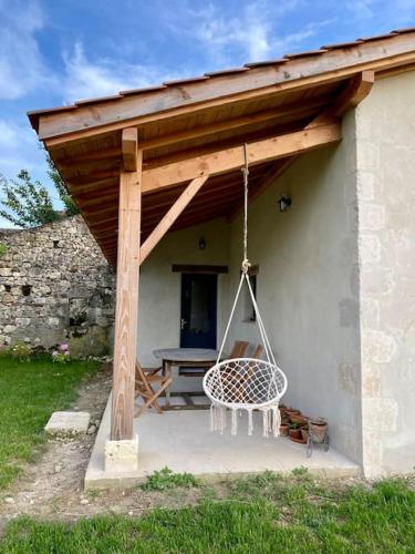 a porch with a swing and a picnic table at Maison de charme à la campagne in Montpezat
