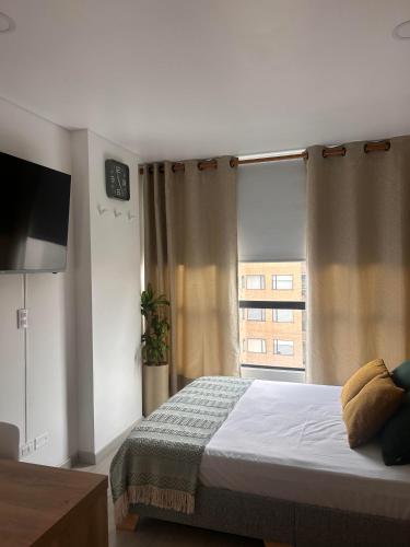 a bedroom with a bed and a large window at Apartamento con piscina climatizada, excelente ubicación, luz natural, acogedor y con estilo in Bogotá