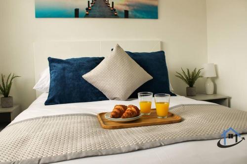 a tray of croissants and two glasses of orange juice on a bed at Beckleigh House, Kettering king or twin beds free parking x3 in Kettering