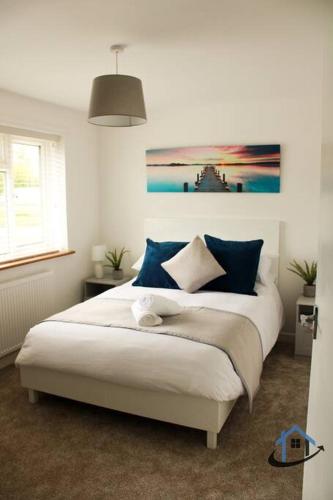 a bedroom with a large white bed with blue pillows at Beckleigh House, Kettering king or twin beds free parking x3 in Kettering