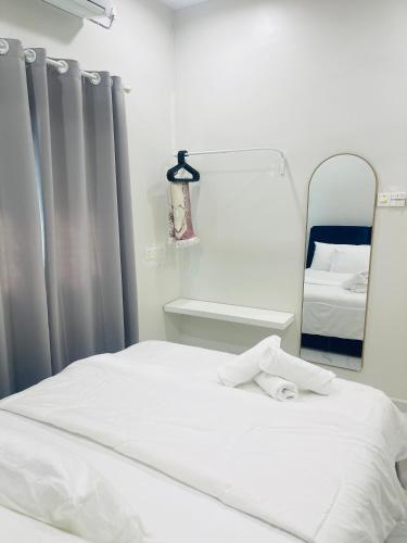 a bedroom with a white bed and a mirror at La Villa in Kampong Ru Sepuloh