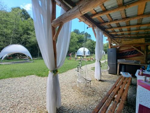 布拉索夫Forest Glamping的凉亭下的木凳，凉亭里搭着帐篷