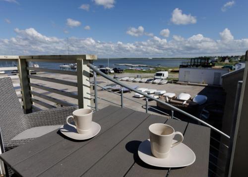 two cups of coffee sitting on a table on a balcony at Grand Holm Marina Kipperi apartment in Haapsalu