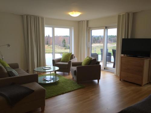 a living room with a tv and a couch and chairs at Sand Golf Club in Bankeryd