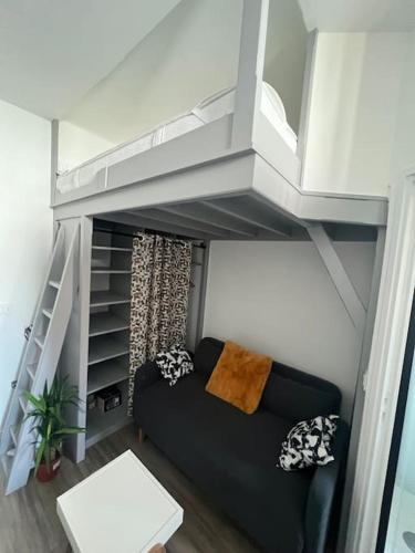 un salon avec un canapé noir dans une mezzanine dans l'établissement Studio refait à neuf en plein Paris !, à Paris
