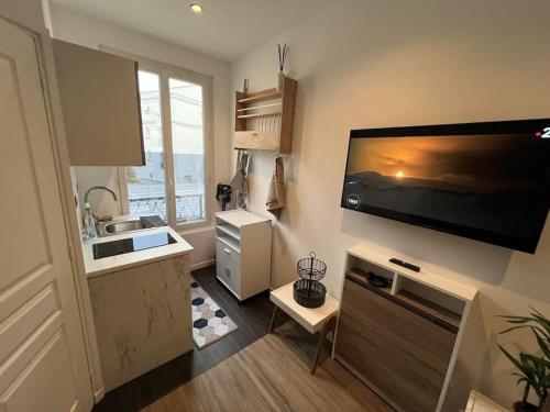 une cuisine avec une grande télévision murale à écran plat dans l'établissement Studio refait à neuf en plein Paris !, à Paris