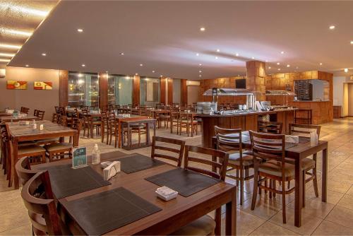 a restaurant with wooden tables and wooden chairs at Hotel Deville Express Cascavel in Cascavel