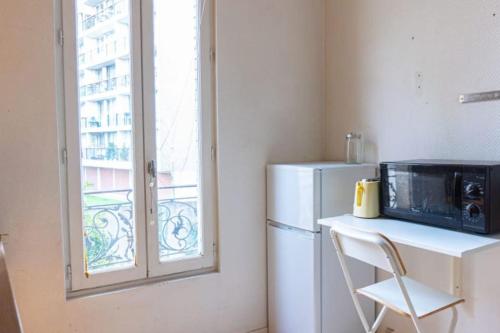 une cuisine avec un réfrigérateur blanc et une fenêtre dans l'établissement calm retreat near Montrouge, à Villejuif