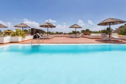 a swimming pool with chairs and umbrellas at Golf y Mar B Suites in Costa Teguise