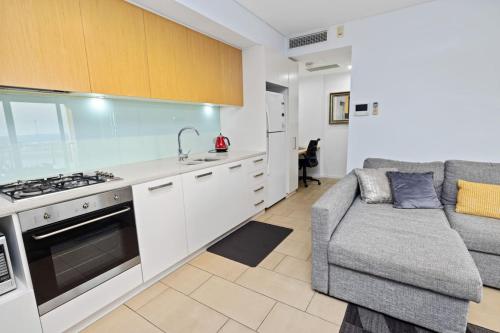 a kitchen with a couch and a stove top oven at Woodys at the Waterfront in Darwin