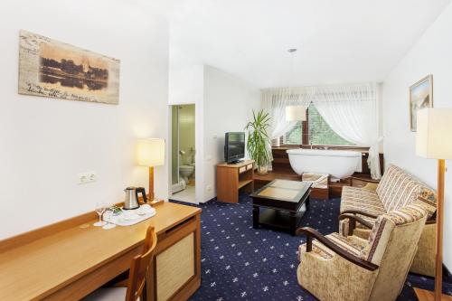 a hotel room with a bath tub and a living room at Park Villa in Vilnius