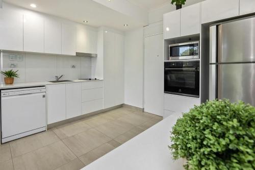 una cucina con armadi bianchi e una pianta in vaso di Seaside Escape - 1BR Hideaway a Fannie Bay