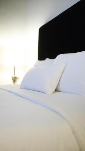 a white bed with white sheets and pillows at El Golf Hotel Boutique in Lima