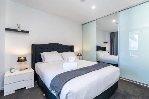 a bedroom with a large white bed and a mirror at Park Avenue Apt in the Heart of the City - Hosted by CanStay in Canberra
