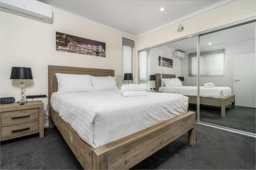 a bedroom with two beds and a mirror at 2BR Apt in the heart of the Gungahlin Town Centre - Hosted by CanStay in Harrison