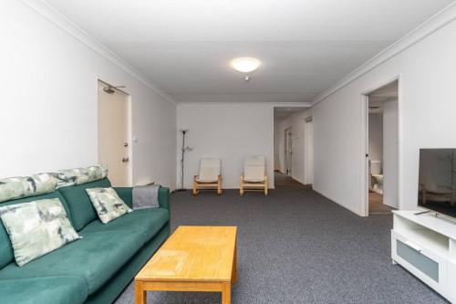 a living room with a green couch and a table at 2BR Apartment Close to Glebe Park and Canberra City - Hosted by CanStay in Canberra