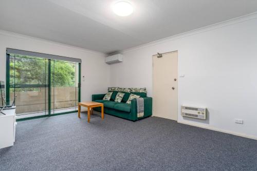a living room with a green couch and a table at 2BR Apartment Close to Glebe Park and Canberra City - Hosted by CanStay in Canberra