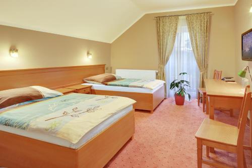 a hotel room with two beds and a desk at Penzion Harmonie in Žlutice