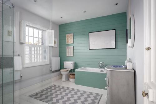 a bathroom with green walls and a toilet and a sink at Village Family home in Midhurst