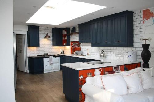 a kitchen with blue cabinets and a white couch at Village Family home in Midhurst