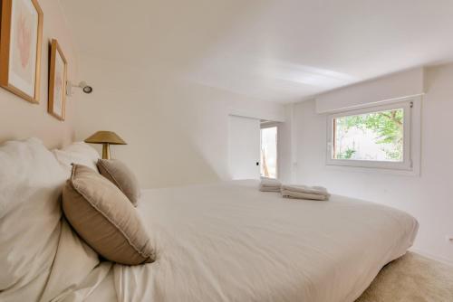 une chambre blanche avec un grand lit avec une fenêtre dans l'établissement Paris Garden Luxury next to Eiffel Tower, à Paris