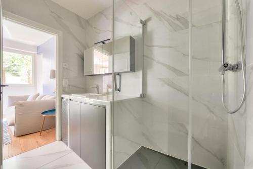 une salle de bain blanche avec une douche et un lavabo dans l'établissement Paris Garden Luxury next to Eiffel Tower, à Paris