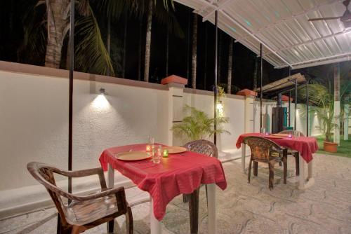 a restaurant with two tables and chairs with red table cloth at Hotel Snehaprabha - Near to Nagaon Beach Alibaug in Alibaug