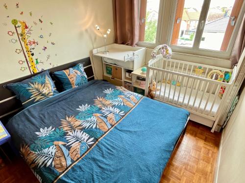 une chambre de bébé avec un berceau et un lit bleu dans l'établissement Sweet Home 1mn Train RER A et 10mn de Paris, à Houilles