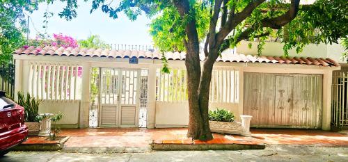 a house with a tree in front of a fence at Casa Nora Alojamiento Entero, 4 Habitaciones Capacidad Máxima 9 huéspedes in Ríohacha