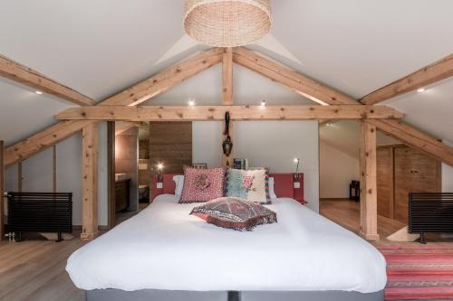 Cette chambre comprend un grand lit blanc et des poutres apparentes. dans l'établissement Chalet Moussoux - Hammam prive, à Chamonix-Mont-Blanc