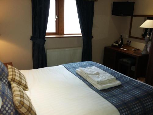 a bedroom with a bed with two towels on it at The Huntsman Inn in Holmfirth