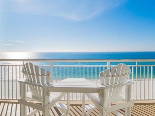 two white chairs sitting on a balcony overlooking the ocean at The Pearl of Navarre #1403 in Navarre