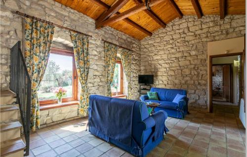 a living room with two blue chairs and a stone wall at Cozy Home In Ragusa With Kitchen in Camemi