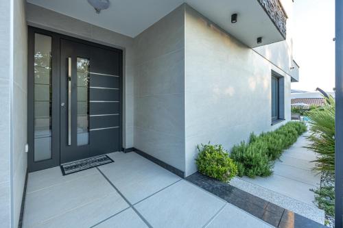a front porch of a house with a black door at Luxury White Sails Villas with a Multi Sport Court #2026# and Sea View in Pinezici