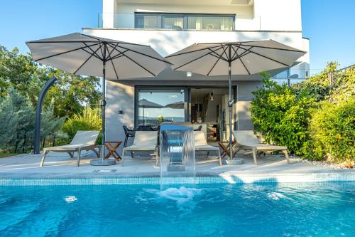 a swimming pool with two umbrellas and a table and chairs at Luxury White Sails Villas with a Multi Sport Court #2026# and Sea View in Pinezici