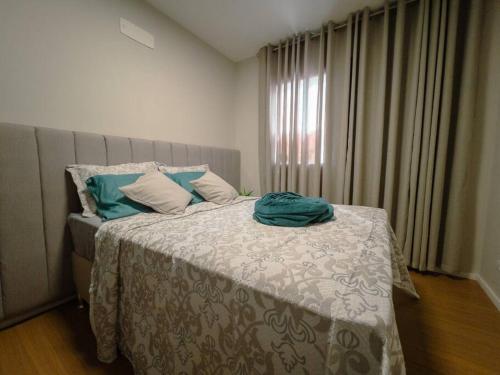 a bedroom with a bed with blue pillows on it at Apto Lindo prox Hospital Paraná AZ104 in Maringá