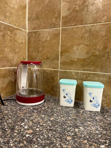 three cups on a counter next to a blender at Uptown urban apartment in Jerash
