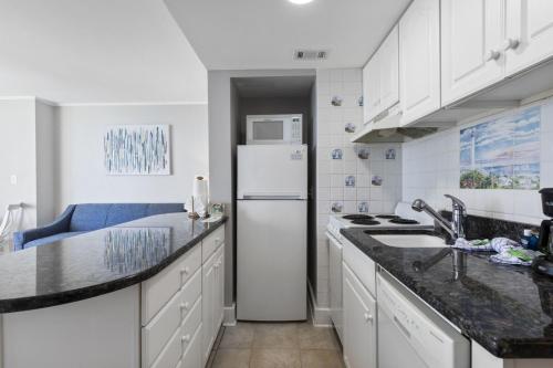 a kitchen with white cabinets and a white refrigerator at Spectacular Oceanview Condos in Myrtle Beach